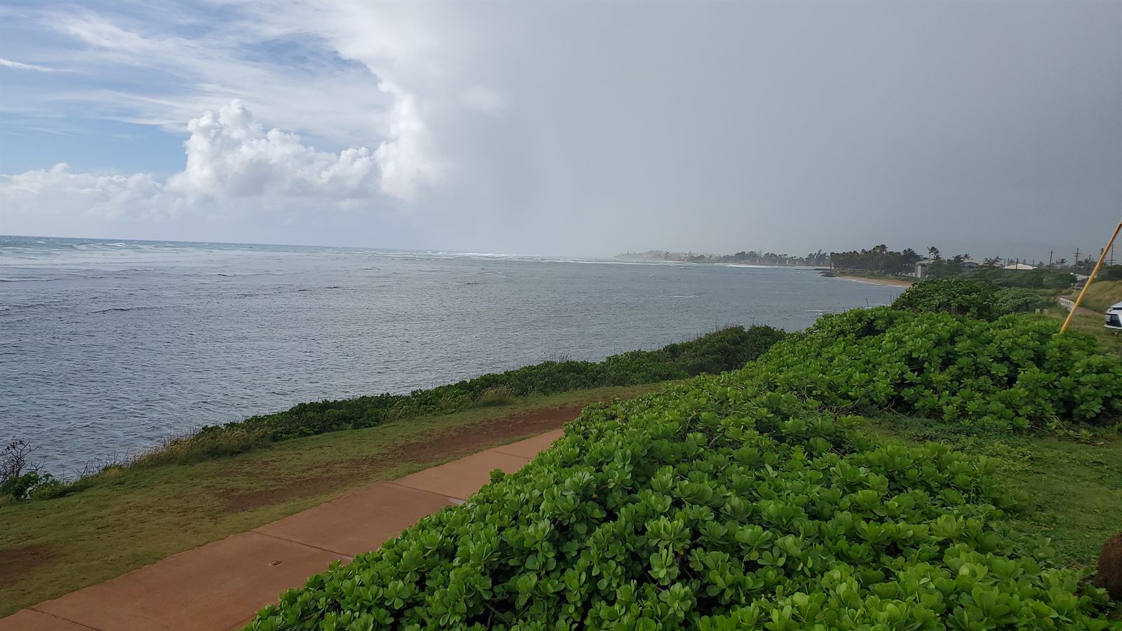 Rain squall moving in over the sea beside a green coastal path