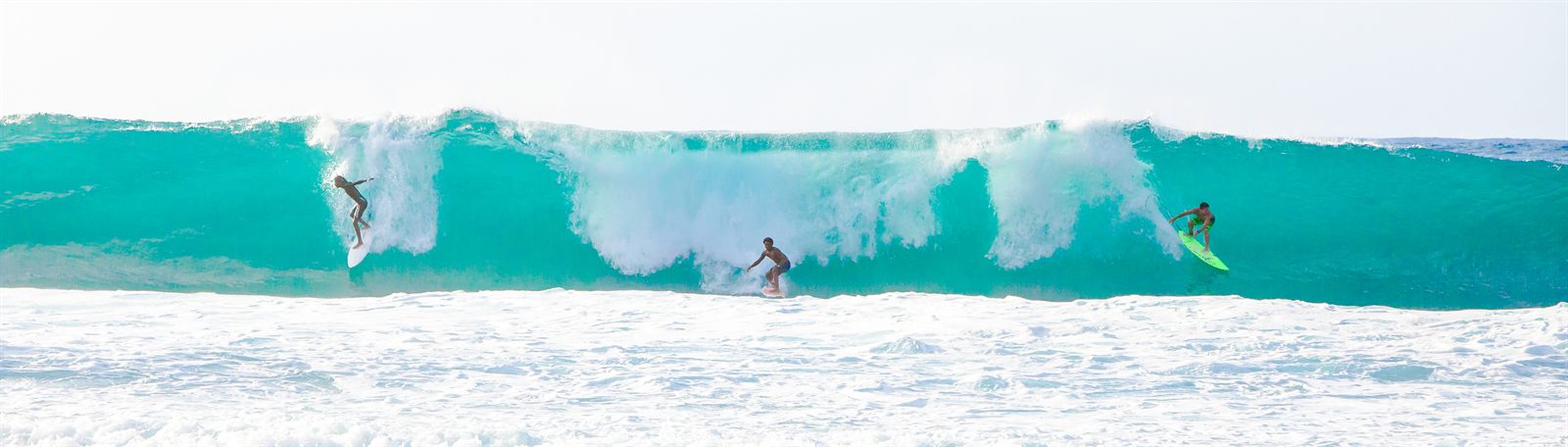Large turquoise wave breaking along an open ocean shoreline